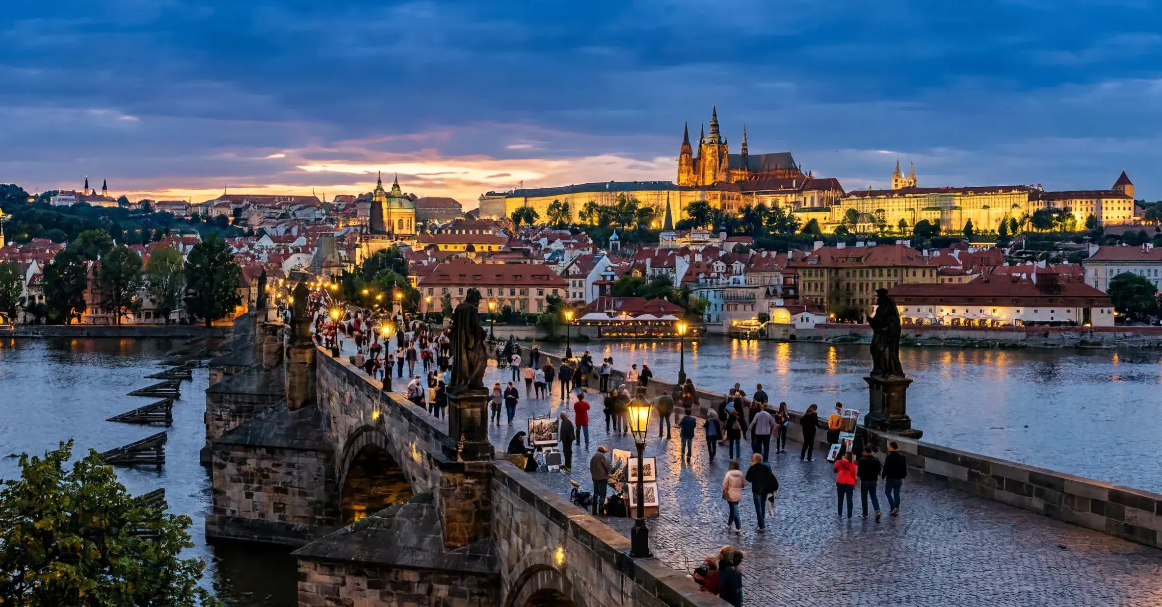 Private transfer from Salzburg Airport or Salzburg city to Prague Charles Bridge over the Vltava River with Prague Castle and St Vitus Cathedral illuminated at dusk